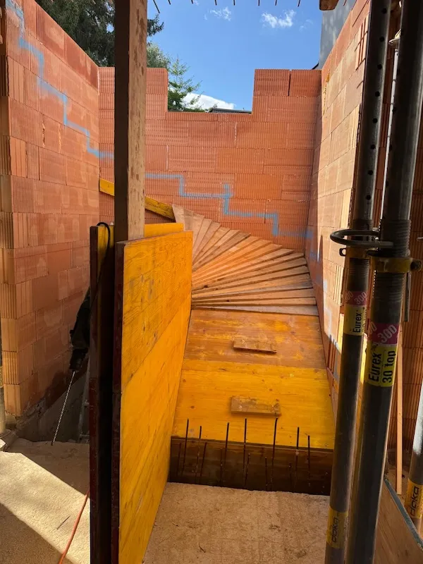 bau einer treppe mit ziegelwänden und gelber schalung im rohbau
