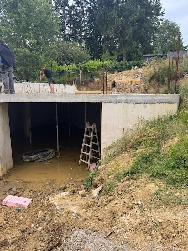 tiefbau bauarbeiter auf betonfundament mit wassergefülltem kellerbereich