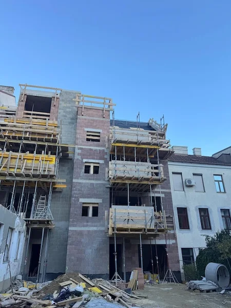 neubau mehrfamilienhaus mit gerüsten und baumaterial auf der baustelle