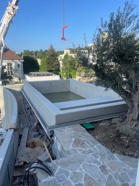 pool aus sichtbeton im bau mit umgebender steinmauer und olivenbaum